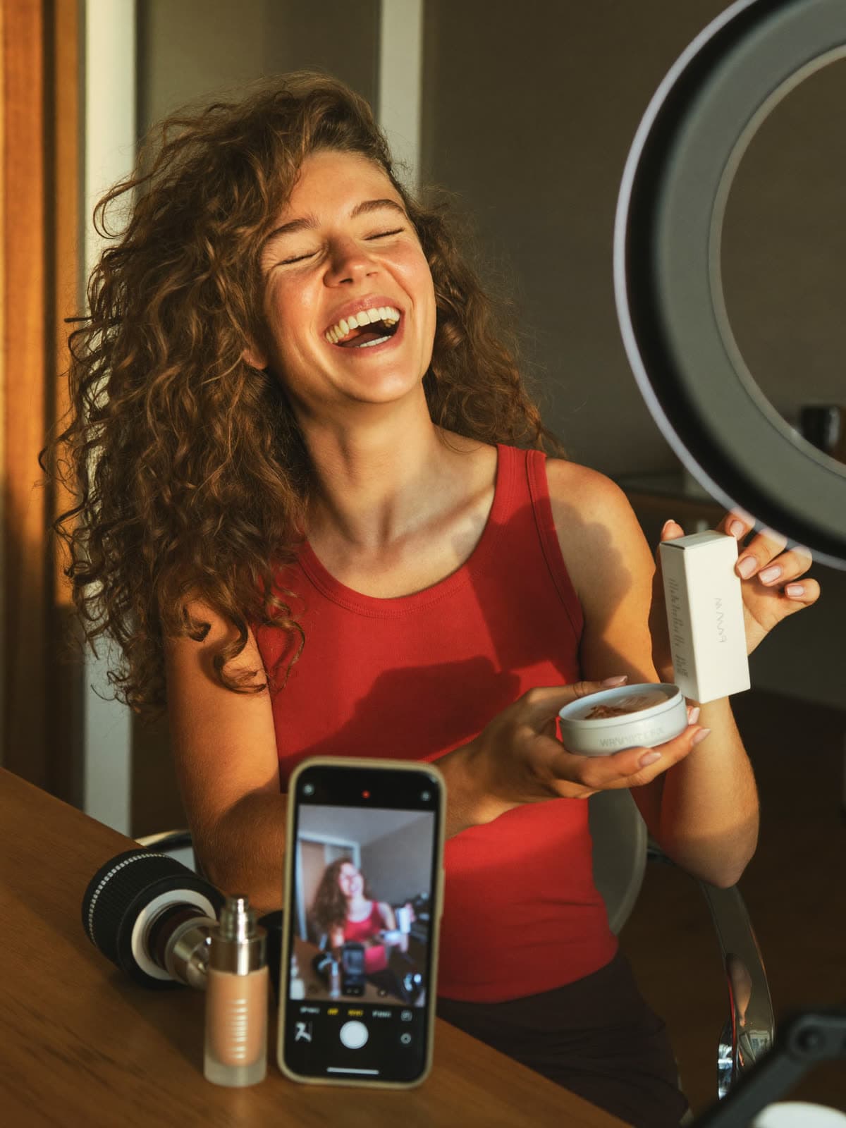 A creator laughs while unboxing a product on camera in her home studio