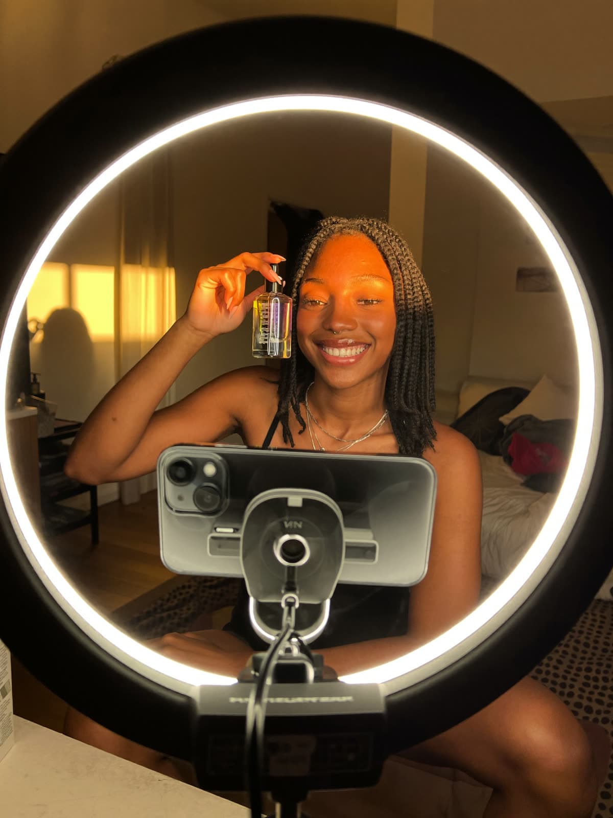 A creator films herself with a serum on a phone tripod under a ring light