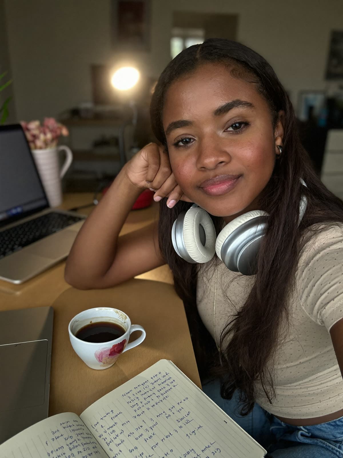 A creator relaxes at her desk with coffee and her notebook