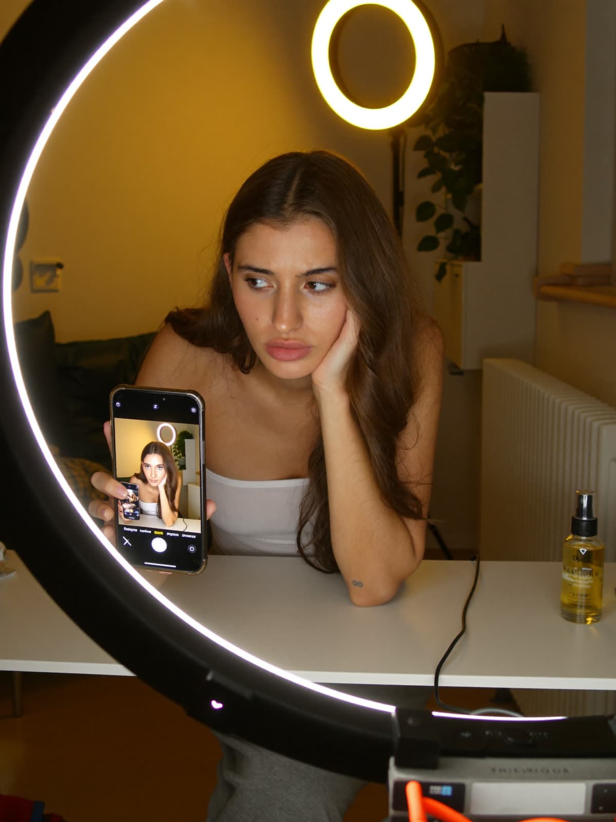 A creator reviews a video on her phone at her desk before posting it